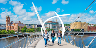 Image of 3 people walking across the Peace Bridge in Derry