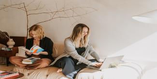 Two women sitting reading and on a laptop