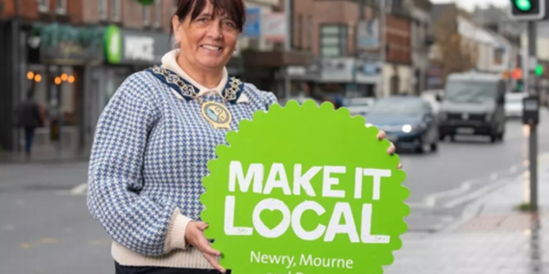 Image of a woman holding a 'Make it Local' sign for Newry, Mourne & Down Council