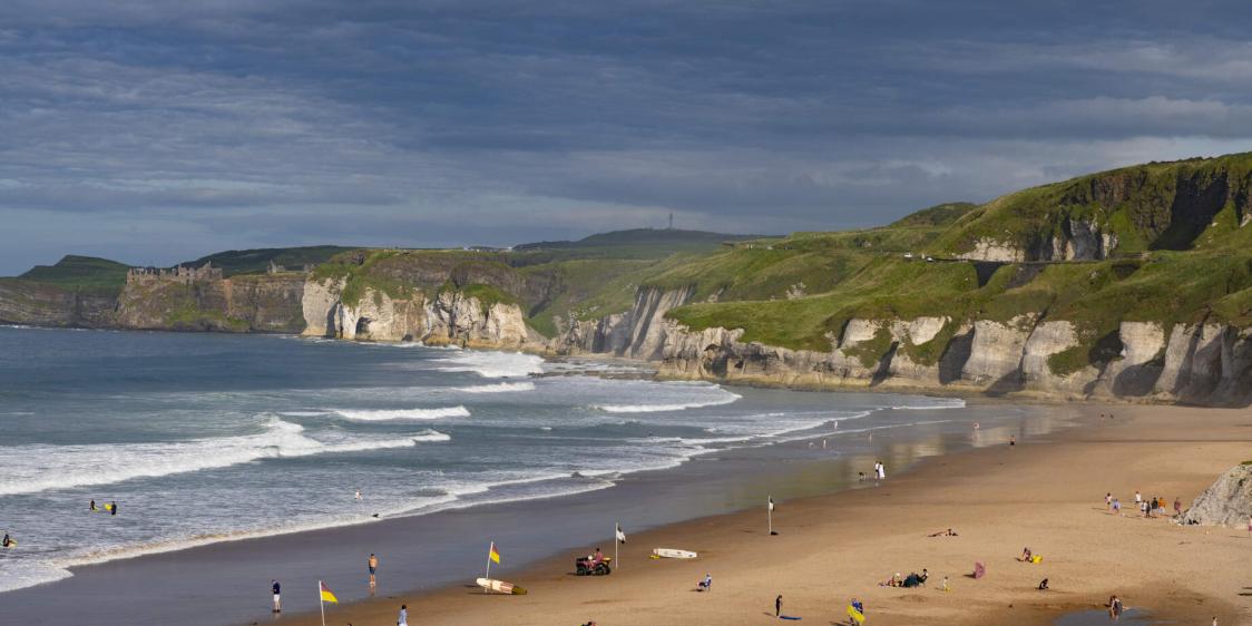 Scenic view of Whiterocks Beach in Portrush with cliff backdrop.