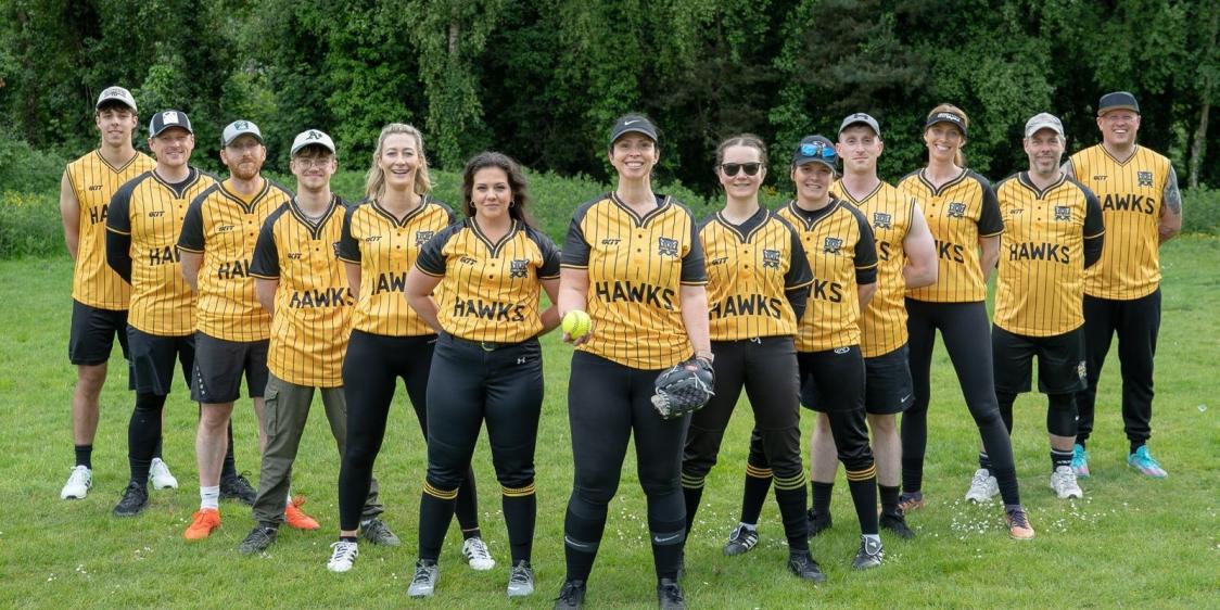 Lisburn Hawks Softball Team standing in a V-formation and smiling to camera. 