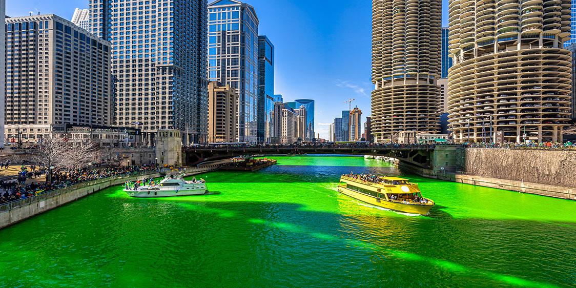 Chicago River dyed bright green with boats passing through the city’s downtown skyline.