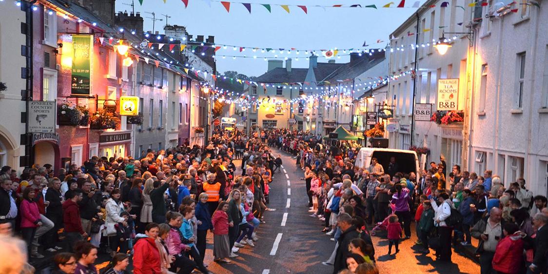 Crowds gather on a bunting-lined village street during a summer festival in Northern Ireland.