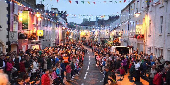 Crowds gather on a bunting-lined village street during a summer festival in Northern Ireland.